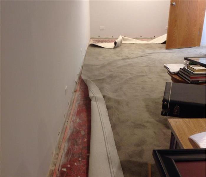room with carpet pulled up and contents on table